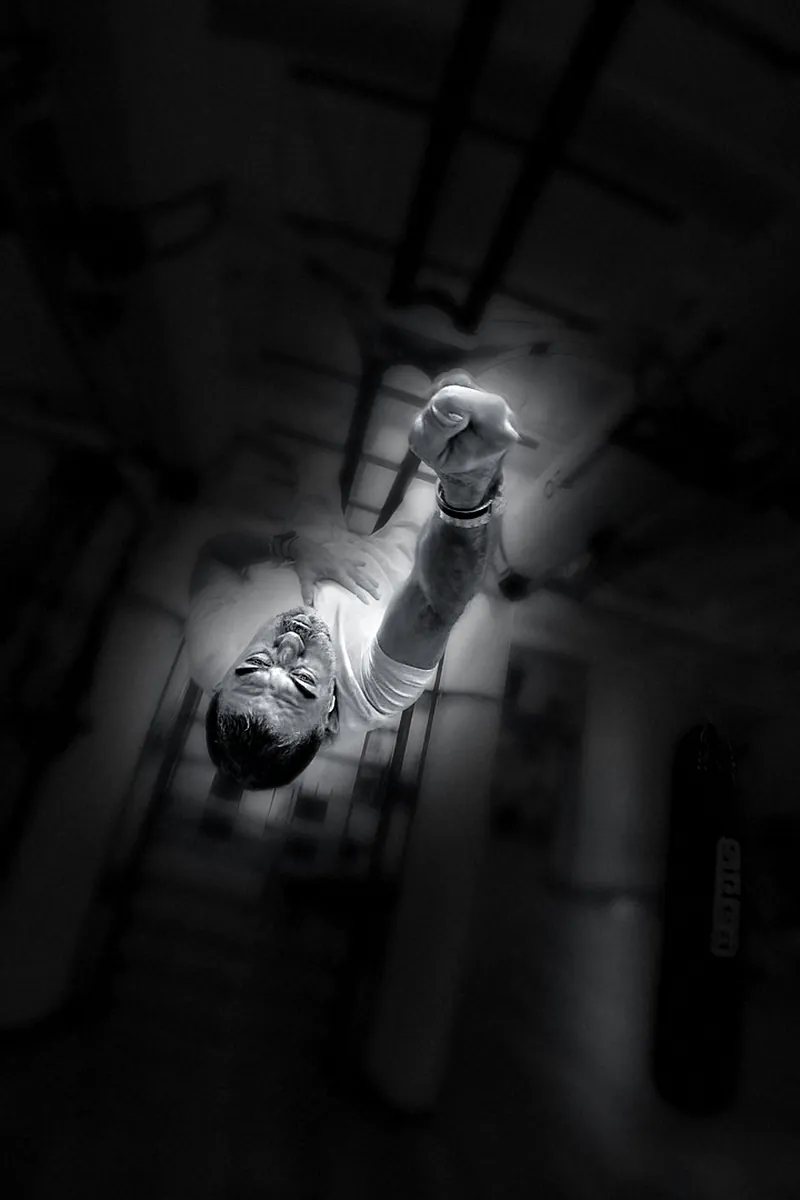 Houman Farzian upside down on the bar, smiling with his fist up, black and white
