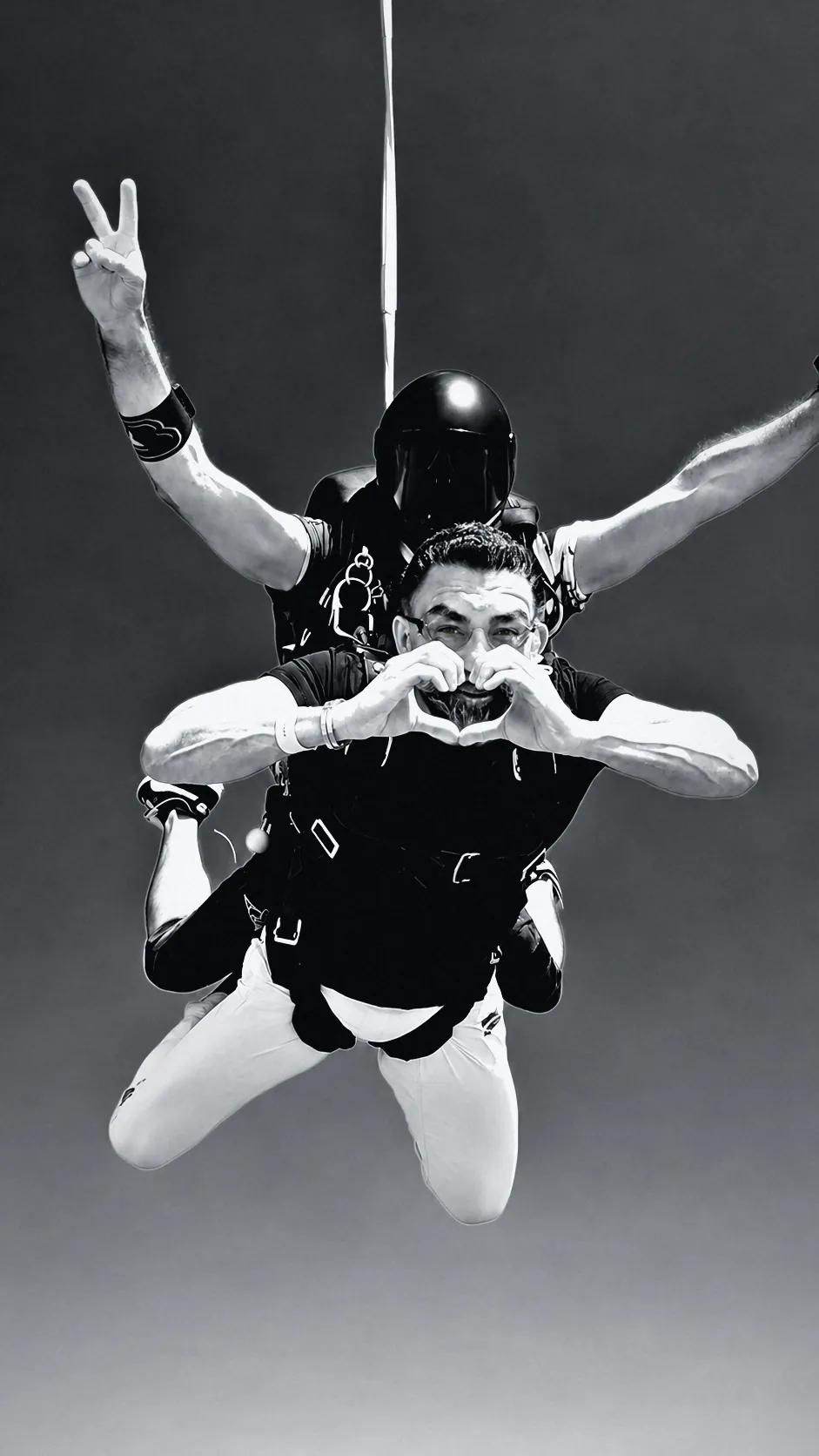Houman Farzian making a heart with his hands in tandem freefall, black and white